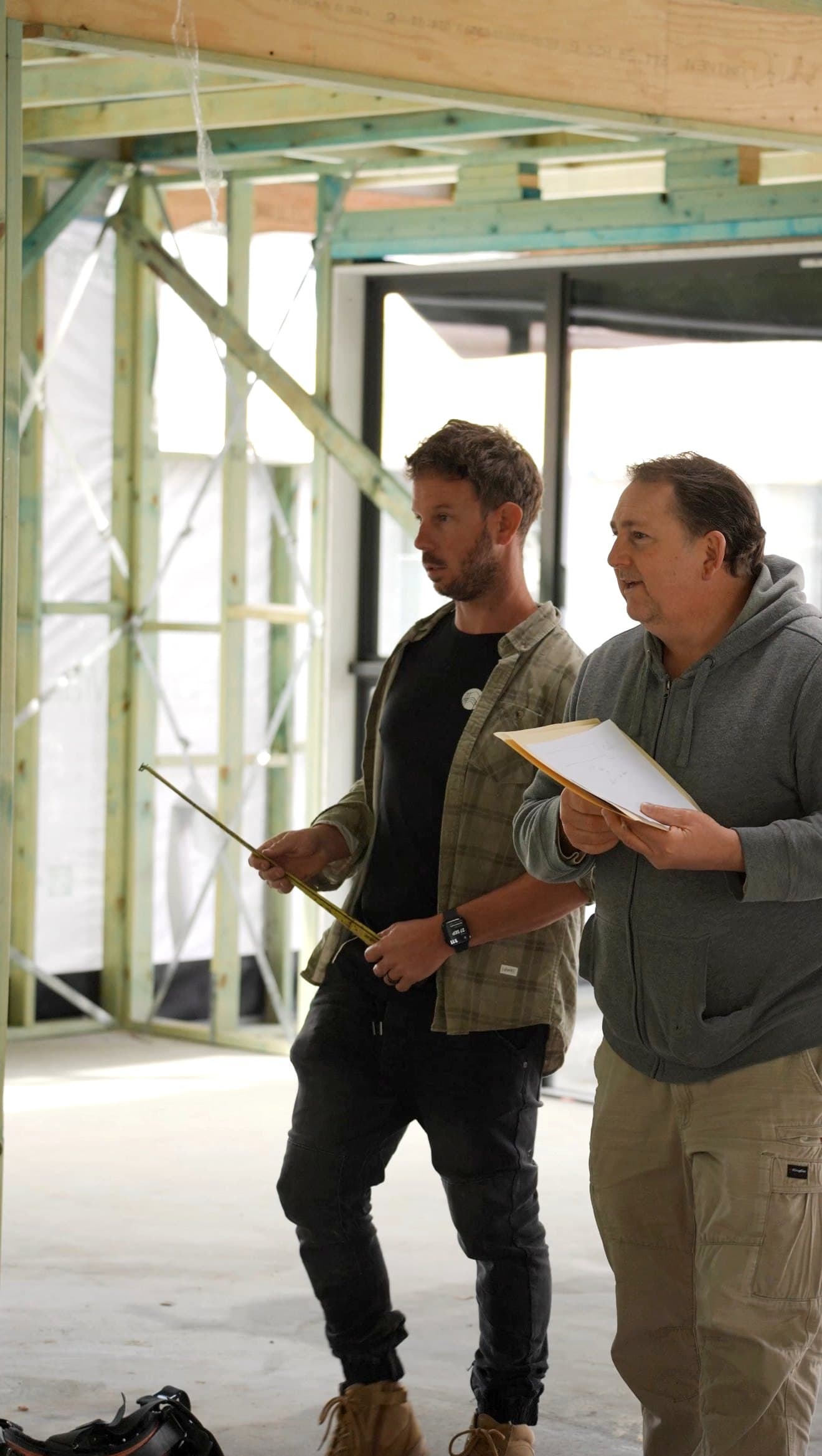 Hills Homes team reviewing plans inside a house frame on site