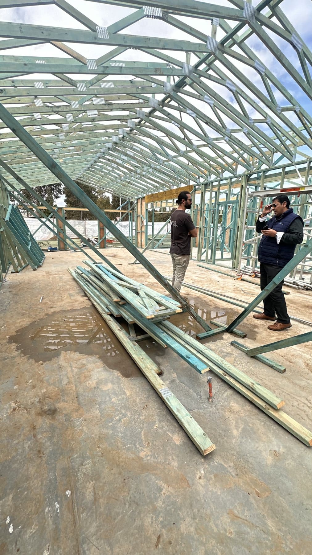 Hills Homes site meeting inside a house frame under the roof trusses